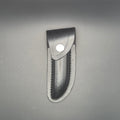 etui noir en croute de cuir posé et en position fermé pouvant accueillir un couteau pliant de 12cm environs