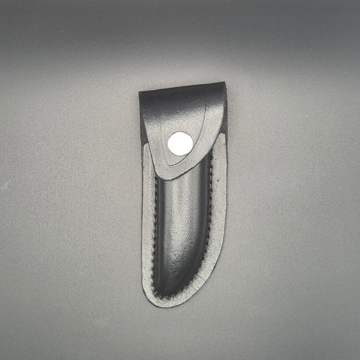 etui noir en croute de cuir posé et en position fermé pouvant accueillir un couteau pliant de 12cm environs