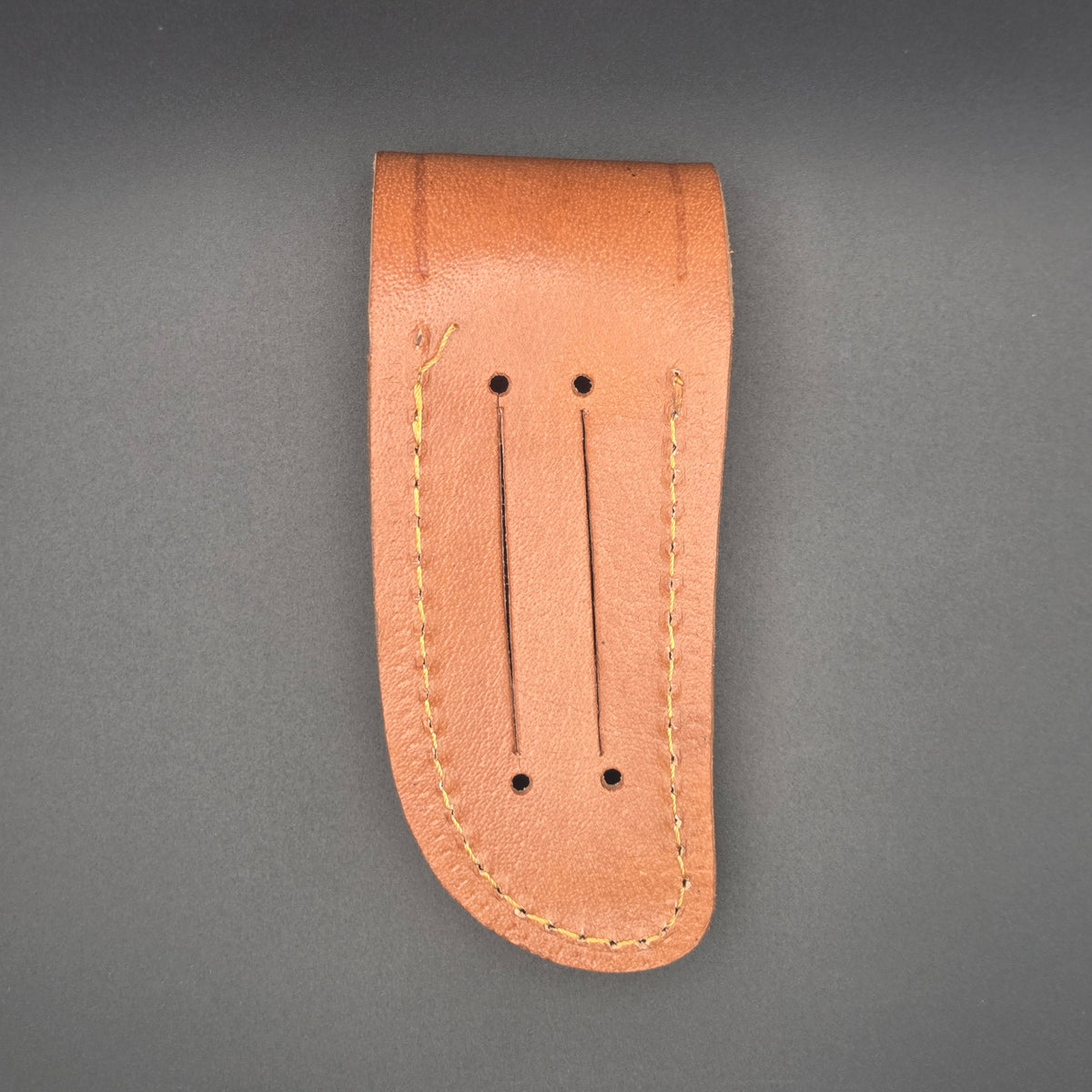 vue arrière d'un étui marron pour couteau en croute de cuir. on voit des rainures permettant de le mettre à la ceinture