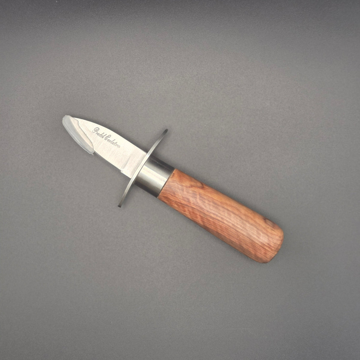 Couteau à huître posé à plat avec son manche en teck avec garde