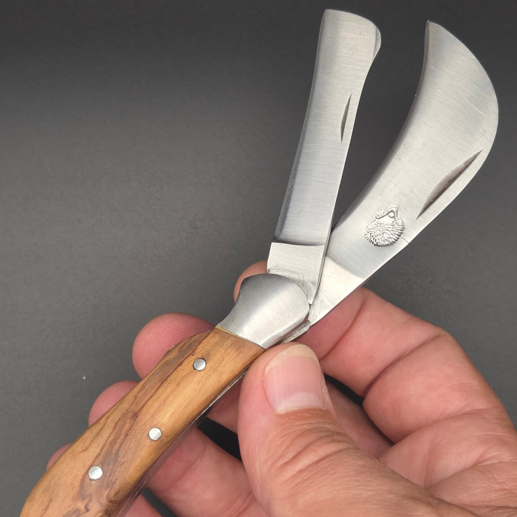 couteau pliant utilitaire servant à la fois de serpette et de greffoir. Sur la lame serpette est gravé un hérisson. Le manche est en teck et la qualité générale  est de 2ème choix.