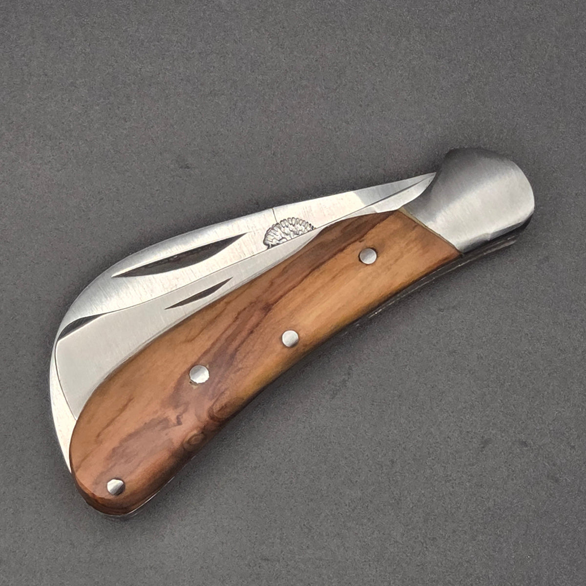 couteau pliant utilitaire serpette et greffoir en même temps posé à plat en position fermé. Il est muni d'un manche en teck et est de qualité second choix