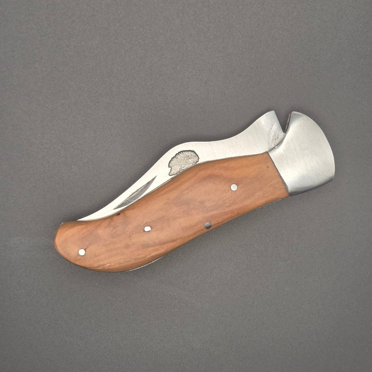 couteau robuste posé à plat en position fermé où l'on voit un hérisson gravé sur la lame. Qualité de second choix.