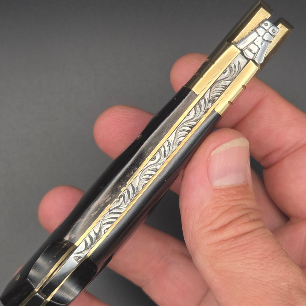 guillochage d'un couteau pliant en lame damas tenu en main