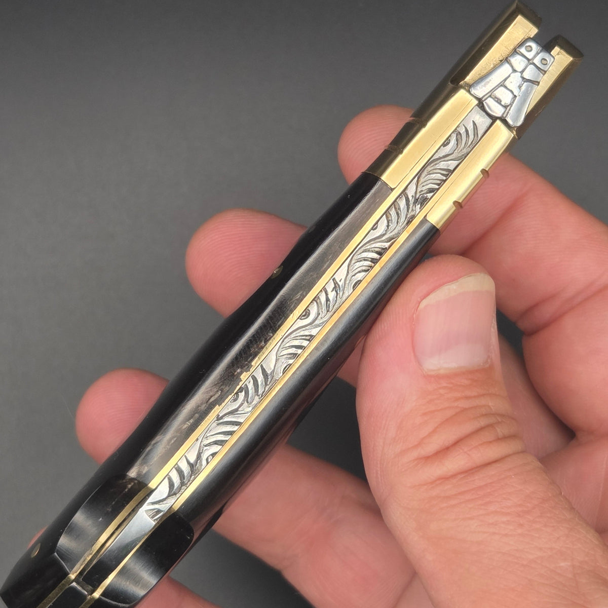 guillochage d'un couteau pliant en lame damas tenu en main