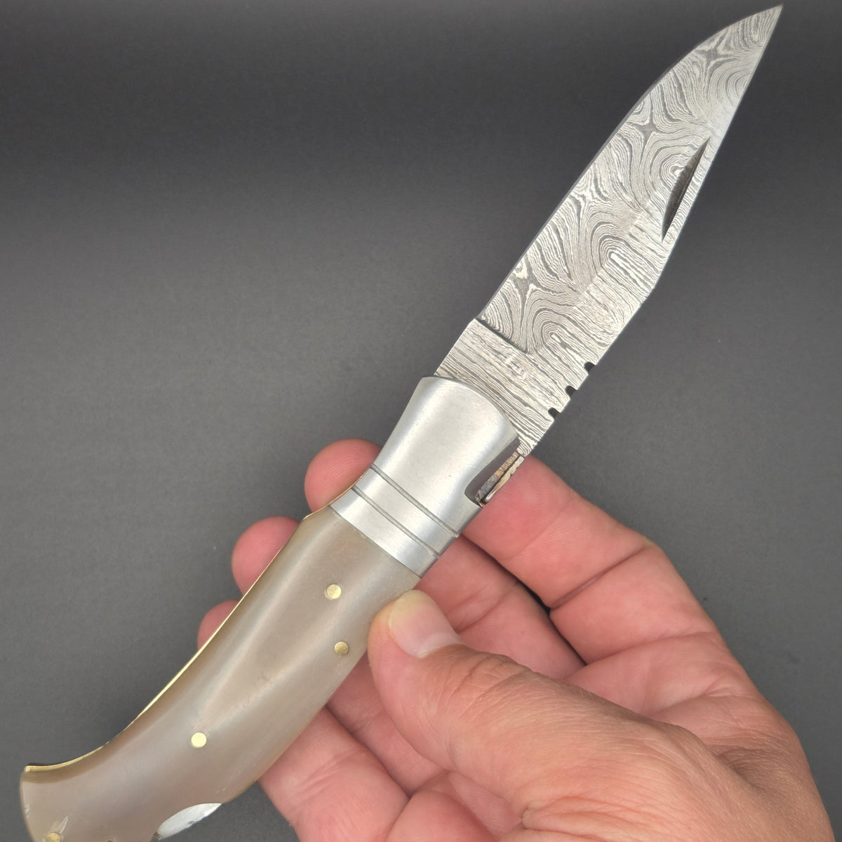 couteau pliant avec lame damas en position ouvert et tenu dans une main