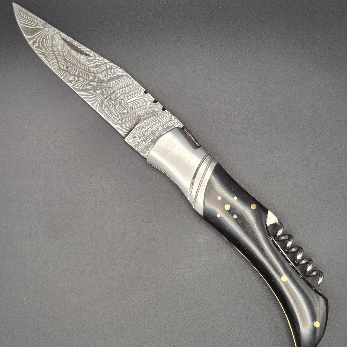 couteau pliant utilitaire muni d'un tire-bouchon et équipé d'une lame en damas.