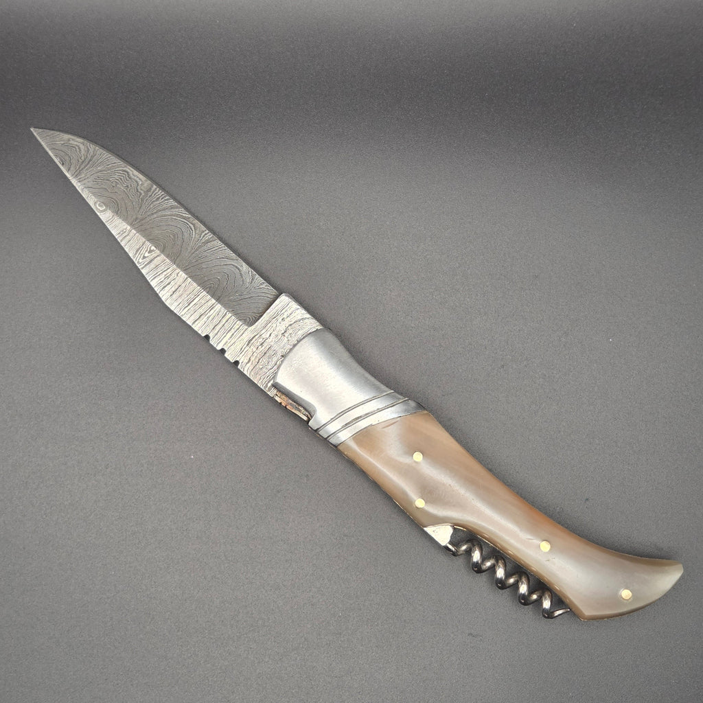 couteau utilitaire pliant avec lame damas et tire-bouchon en position ouverte muni d'un manche en corne blonde