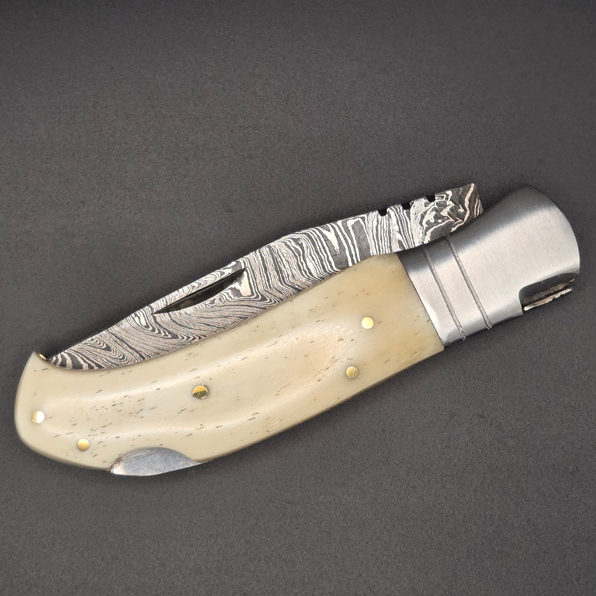 couteau utilitaire pliant avec lame damas en position fermée? Il est muni d'un manche clair en os
