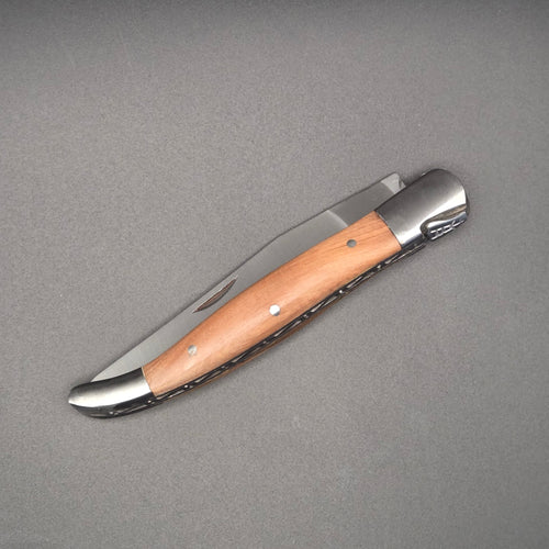 couteau pliant utilitaire élancé posé à plat et en position fermé. Son manche est en teck.