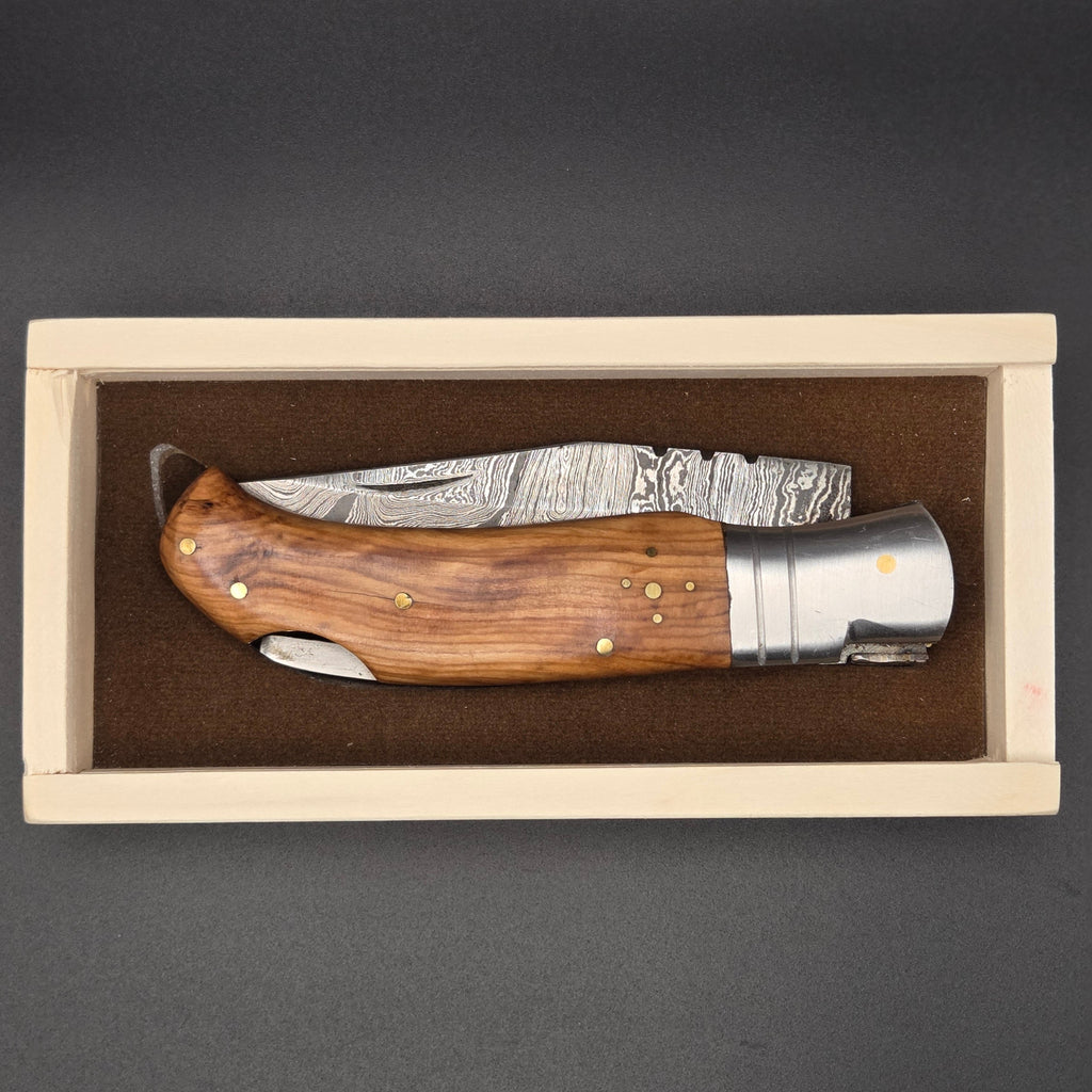 Couteau pliant rangé dans sa belle boite en bois. Il est muni d'une lame en damas et d'un manche en teck