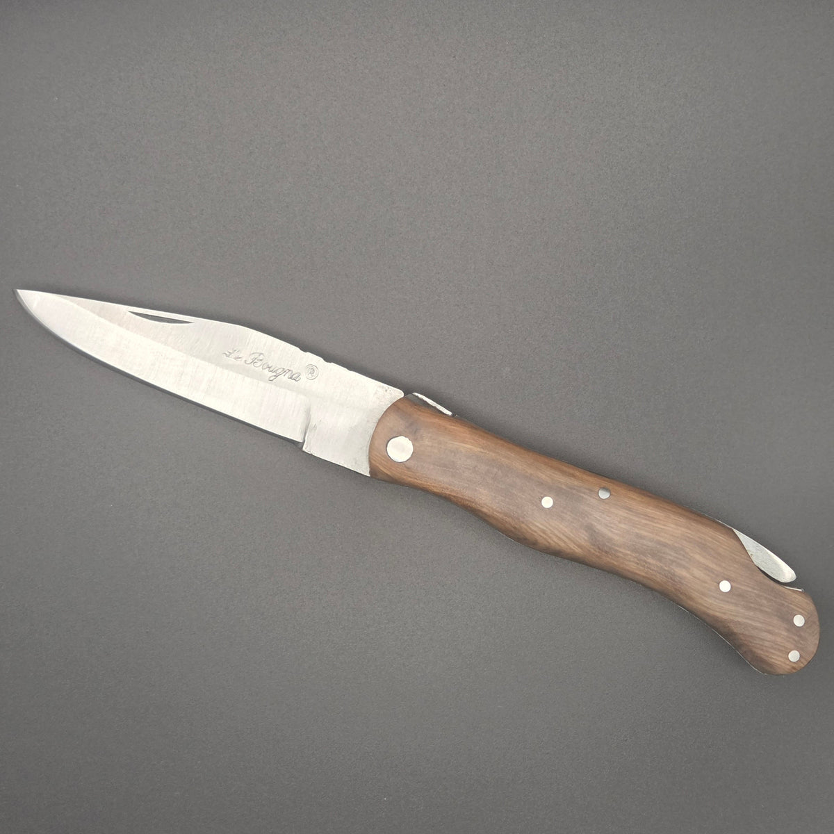 couteau pliant utilitaire rustique posé à plat en position ouvert. Il a un manche en teck.