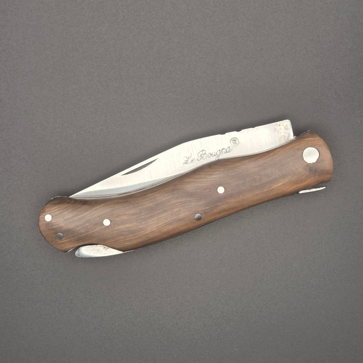 Couteau pliant utilitaire rustique posé en position fermée. On y voit l'incrustation La Bougna sur la lame et son manche en teck.
