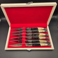 coffret en bois ouvert montrant 6 couteaux de table en inox avec un manche en corne et os.