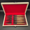 coffret en bois ouvert montrant 6 couteaux de table en inox avec leur manche en teck. Ce sont des couteaux de la marque La Bougna