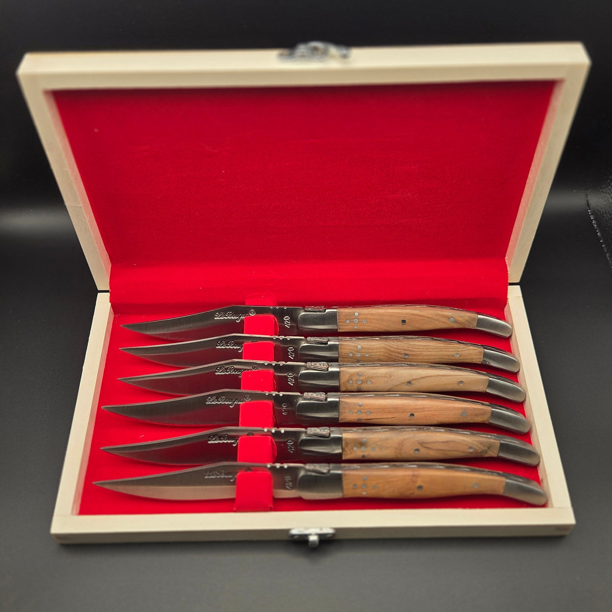 coffret en bois ouvert montrant 6 couteaux de table en inox avec leur manche en teck. Ce sont des couteaux de la marque La Bougna