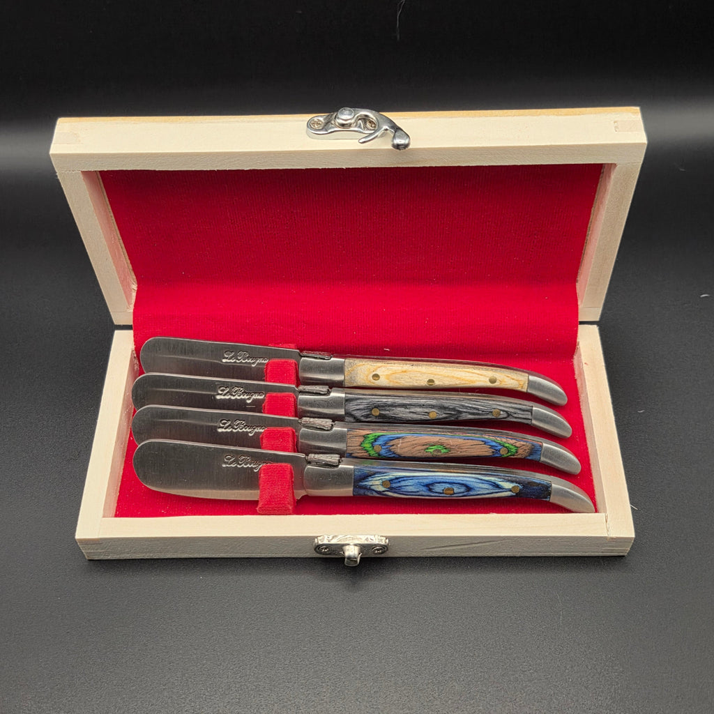 Coffret en bois ouvert dans lequel on peut apercevoir quatre couteaux à beurre avec des manches de couleur différente