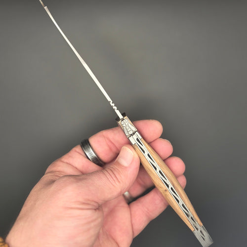 Photo où on voit le guillochage d'un couteau à fromage tenu dans une main