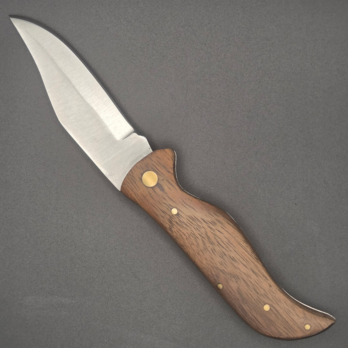 Couteau pliant berger posé à plat en position ouvert. On y voit un joli manche en bois.