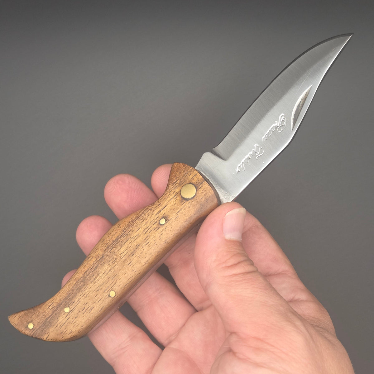 Couteau berger pliant tenu dans une main en position ouvert. C'est un couteau de second choix niveau qualité.