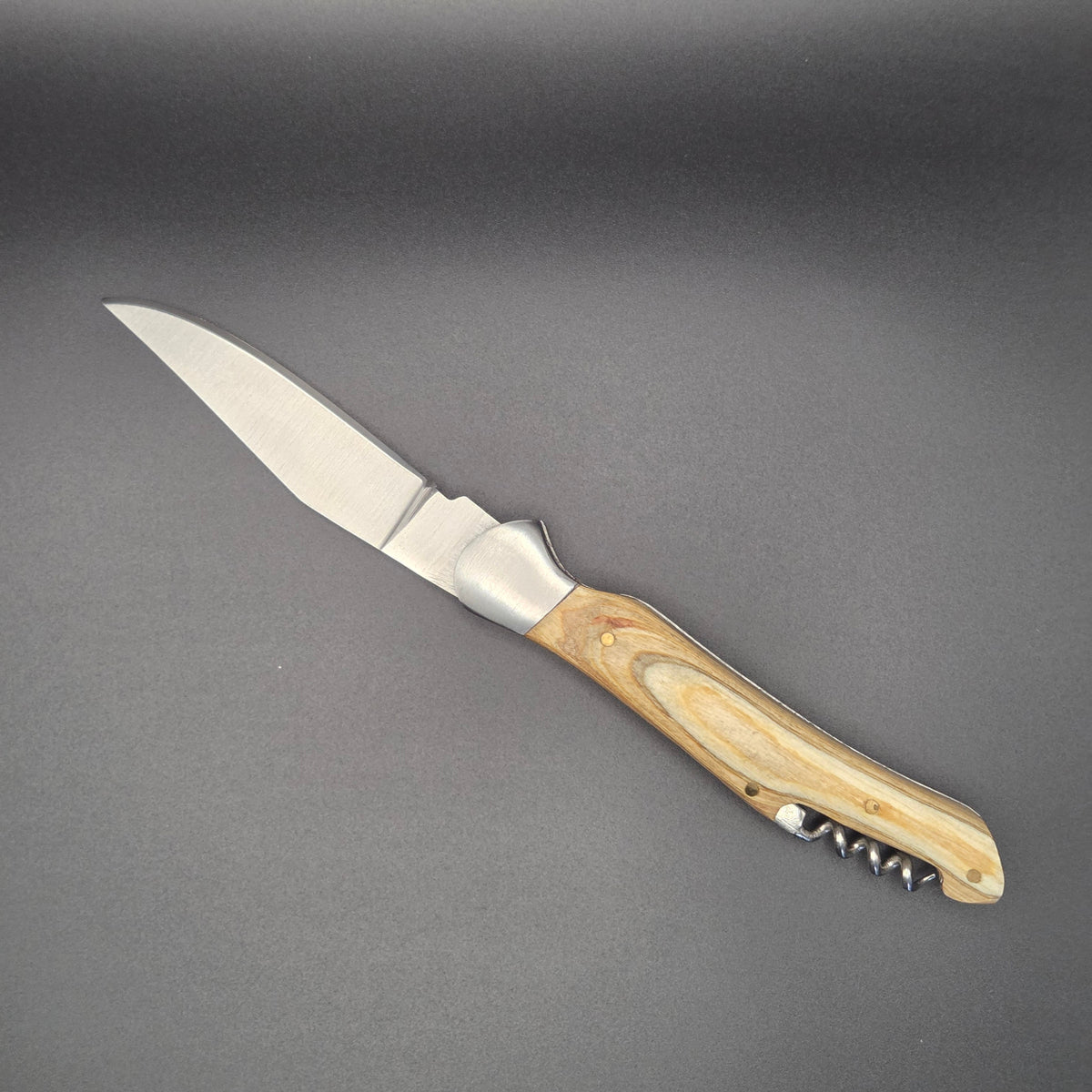 Couteau pliant utilitaire avec manche en teck blanchi muni d'un tire-bouchon posé à plat en position ouvert.