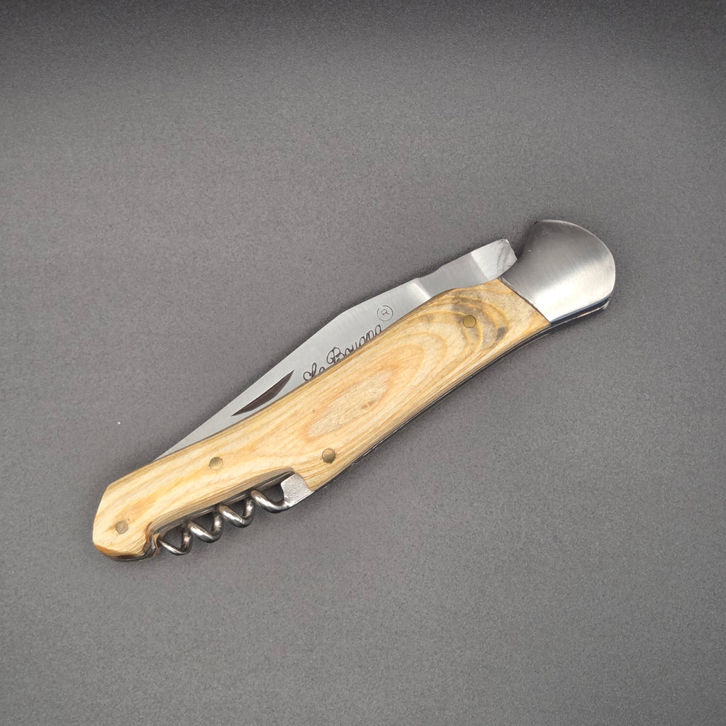 Couteau utilitaire pliant muni d'un manche en teck blanchi et d'un tire-bouchon pratique. Il est posé au sol en position fermé.