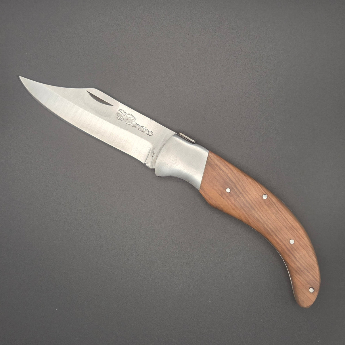 Couteau pliant utilitaire avec son manche incurvé en teck posé à plat en position ouvert. 
