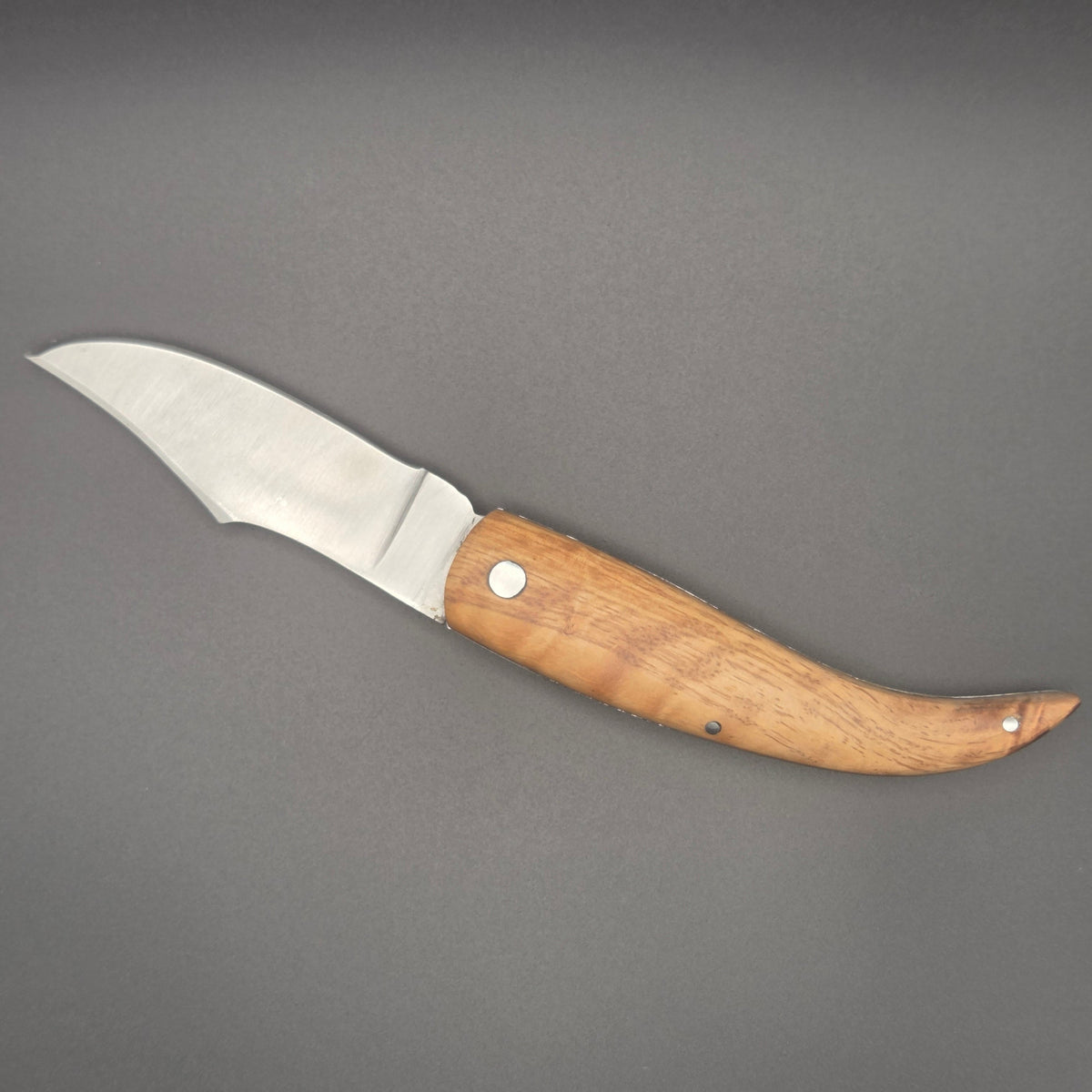 couteau utilitaire pliant posé à plat en position ouvert. Avec manche en teck.