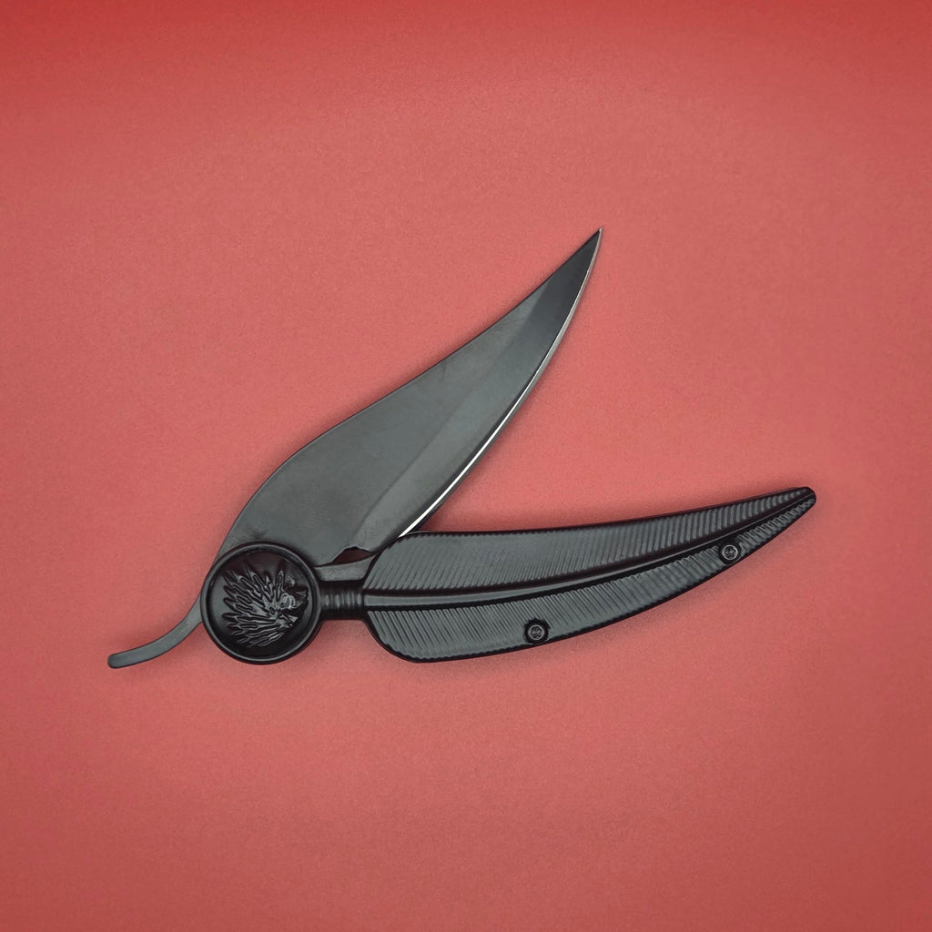 couteau pliant noir en forme de plume. Il est posé légèrement ouvert. Il fait 10 cm
